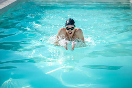 Swimmer, swim. Swimmer in swimming cap and swimming goggles with open mouth, palms in front in water...