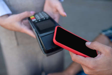 Paying bill. Close-up of male customer paying bill with smartphoneの写真素材