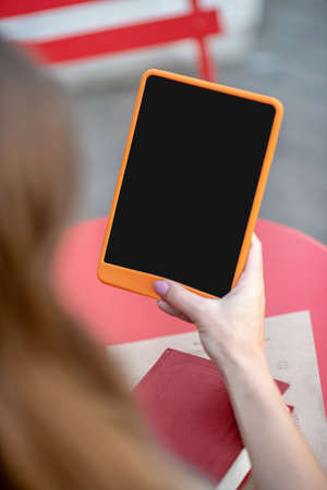 pleasnt time. Close-up of female hands holidng orange tablet above tableの写真素材