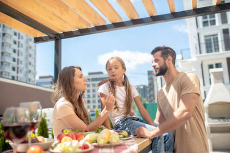 Positive vibes. Young family having dinner outside and looking pleasedの写真素材