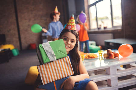 Happy girl. Cute girl in a hat holding presents and looking happyの写真素材