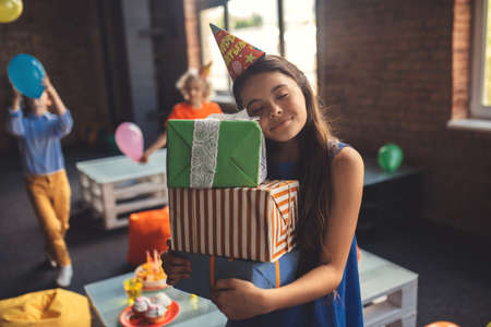 Cute girl in a hat holding presents and smilingの写真素材
