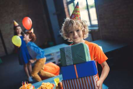Sweet blonde boy holding presents and smilingの写真素材