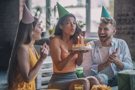 Birthday party. A happy woman blowing out candles on her birthday cakeの写真素材