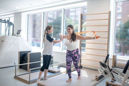 Workout. Dark-haired plus size woman having workout with instructor