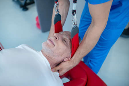 Procedure, massage. Calm elderly man with closed eyes and hands of doctor doing neck massage
