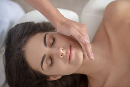 Face massage. Young pretty woman having face massage in the salonの写真素材