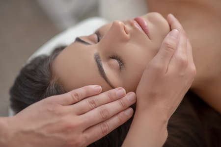 Face massage. Professional massage therapist massaging young womans faceの写真素材