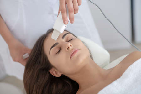 Skin care. Dark-haired woman having laser skin treatment in the clinicの写真素材