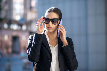 Serious talk. Elegant dark-haired woman looking worried while talking on the phoneの写真素材
