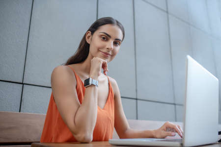 Thoughtful. Dark-haired pretty woman sitting at the laptop