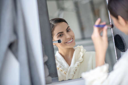 Beauty routine. A young woman applying cosmetics with a brush