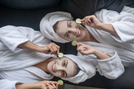 Face care. Young women holding slices of cucumber for face care