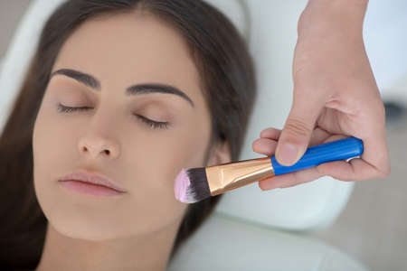 Face care. Cosmetologist applying facial mask on her customers face