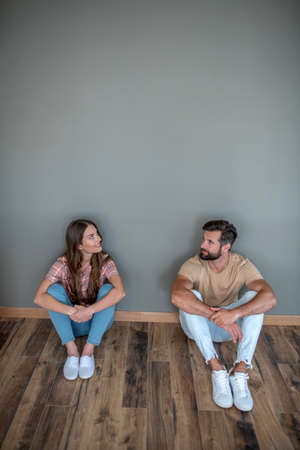 New home. Young couple sitting on the floor in new home and looking contented