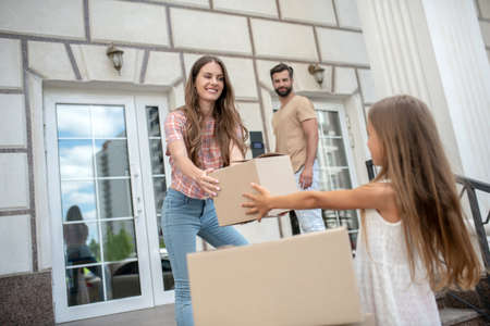 Moving. Mom giving a cardboard to her daughterの写真素材