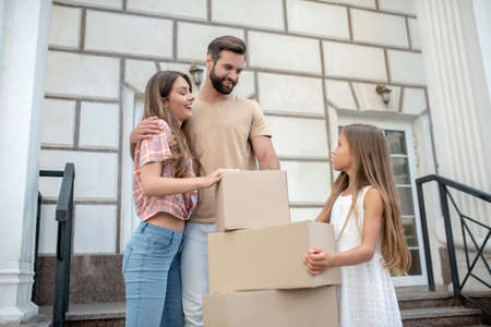 Moving. Young family standing near boxes and feeling excitedの写真素材