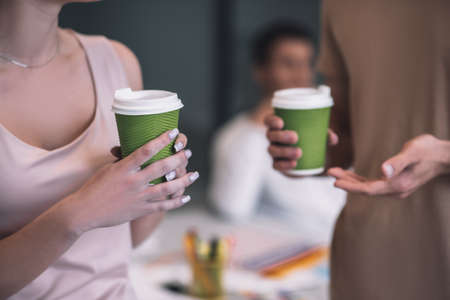 Coffee break. Close up picture of hands holding cupsの写真素材