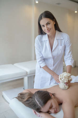 Back massage.Female massage therapist doing bags massage to a female customerの写真素材