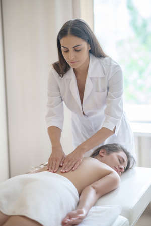 Back massage. Massage therapist rubbing back to a female customerの写真素材