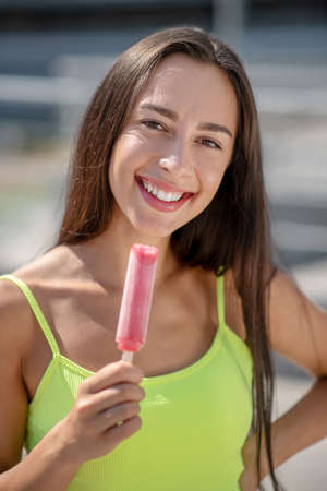 With ice-cream. Girl in yellow top smiling and holding ice-creamの写真素材