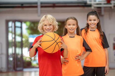 Like to play. Kids in sportswear standing with a ball and looking enjoyedの写真素材