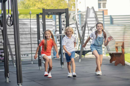 Happy kids. Three friends running at the playground and feeling happyの写真素材