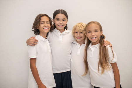 Friends. Schoolchildren standing near the wall and smiling nicely
