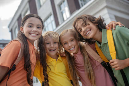 Happy kids. Schoolchildren standing in school yard and looking cheerfulの写真素材