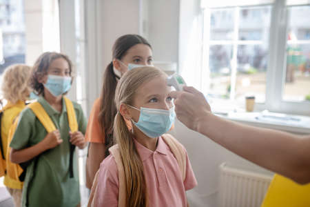 Temperature check up. Schoolchildren passing temperature control while entering the school