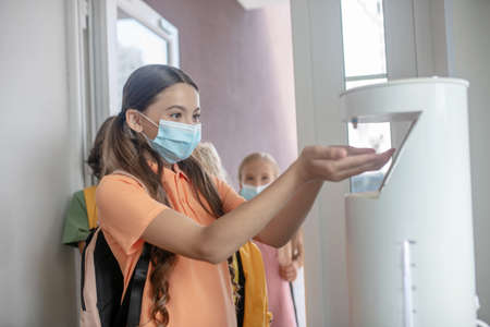 Disinfection. Girl in preventive mask getting some sanitizer into her handの写真素材