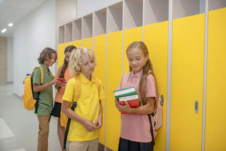Talking. Boy and girl talking in school corridor standing near the lockers