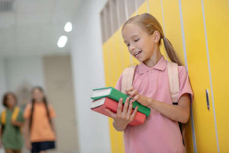 At school. Pretty girl standing near the lockers in school corridor