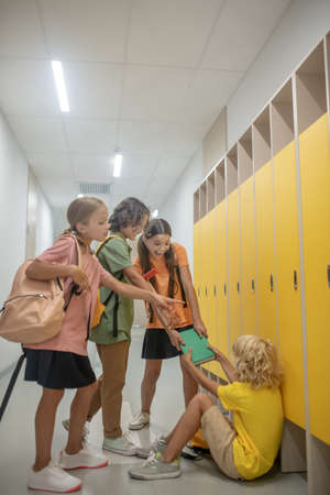 Rudeness. Cruel children pulling the book from blonde boys handsの写真素材