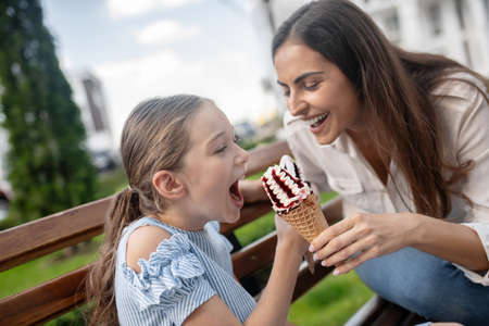 Having fun. Mom and daughter eating ice-cream and having funの写真素材