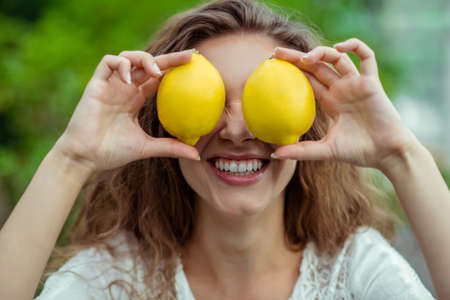 With lemons. Close up of woman with two lemonsの写真素材