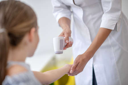 At the doctors. Doctor checking the girls temperature with digital thermometerの写真素材