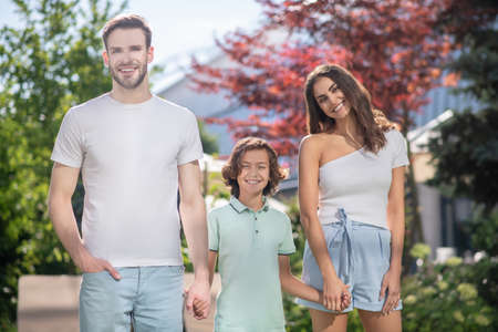 Day off, good day. Young dad and mom with son schoolboy walking holding hands in nature on sunny day