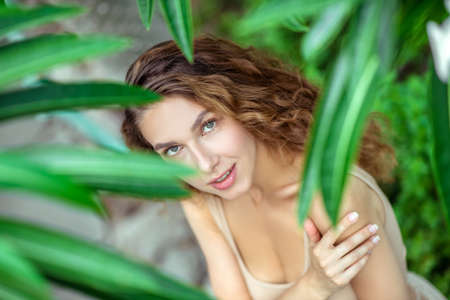 Nature. Young woman standing near the plant and looking beautiful