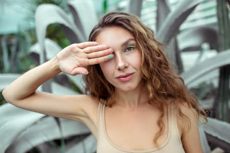 Organic eyeshadows. Pretty young woman closing one eye with her handの写真素材