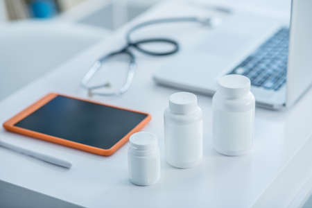 Doctors office. White bottles with medicine and a tablet on the table