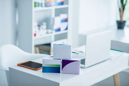 Doctors office. Laptop, tablet and packages with medicines on the tableの写真素材