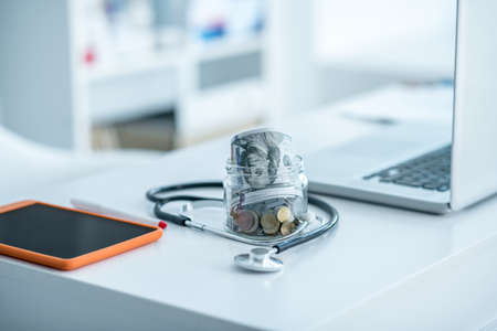 Health insurance. Jar with coins and devices on the tableの写真素材