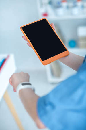 Devices. Close up of a human hand with a smartwatch and a tablet