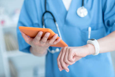 Devices. Close up of person looking at smatwatch and holding a tablet