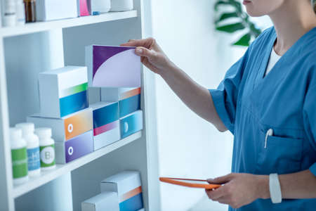 Drug store. Doctor in lab coat searching a package with pills
