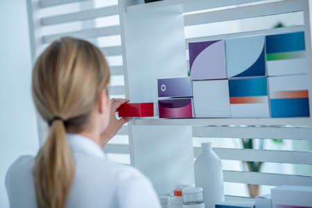 Medicine. Woman in white tshirt taking a medicine from the shelfの写真素材