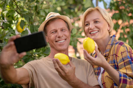 Harvest time. Smiling couple holding lemons, making selfieの写真素材