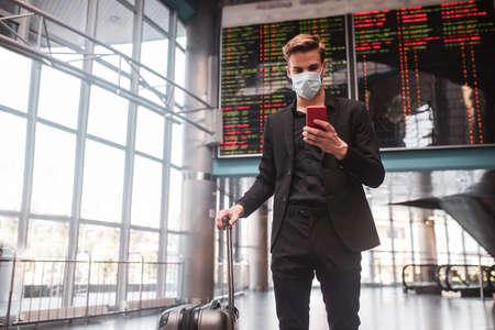 Communication. A man connecting to the wifi in the airport via his smartphoneの写真素材