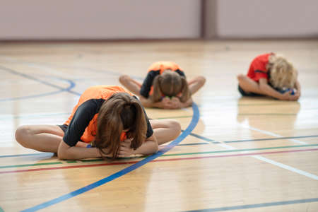 Bending. Three kids in bright sportswear stretching and bending forwardの写真素材